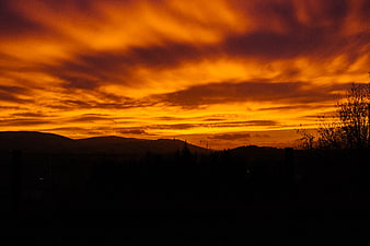 Dramatic fiery orange sunset sky over dark mountain silhouette
