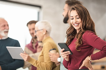 Smiling woman using smartphone in office with colleagues