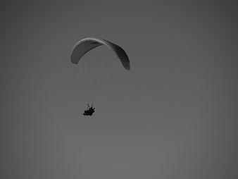 Silhouette of Paraglider Flying Against Gray Sky