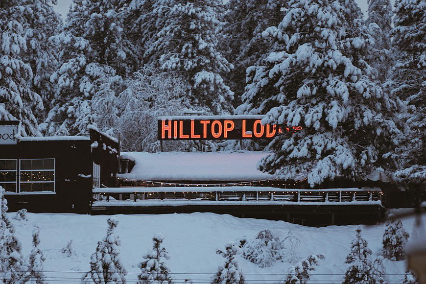 Snowy Hilltop Lodge with Neon Sign in Winter Forest