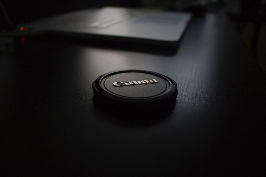 Black Canon Lens Cap on Dark Desk