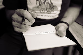 Close-up of hands writing in a notebook