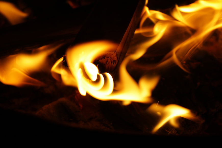 Close-up of burning firewood and bright orange flames in the dark