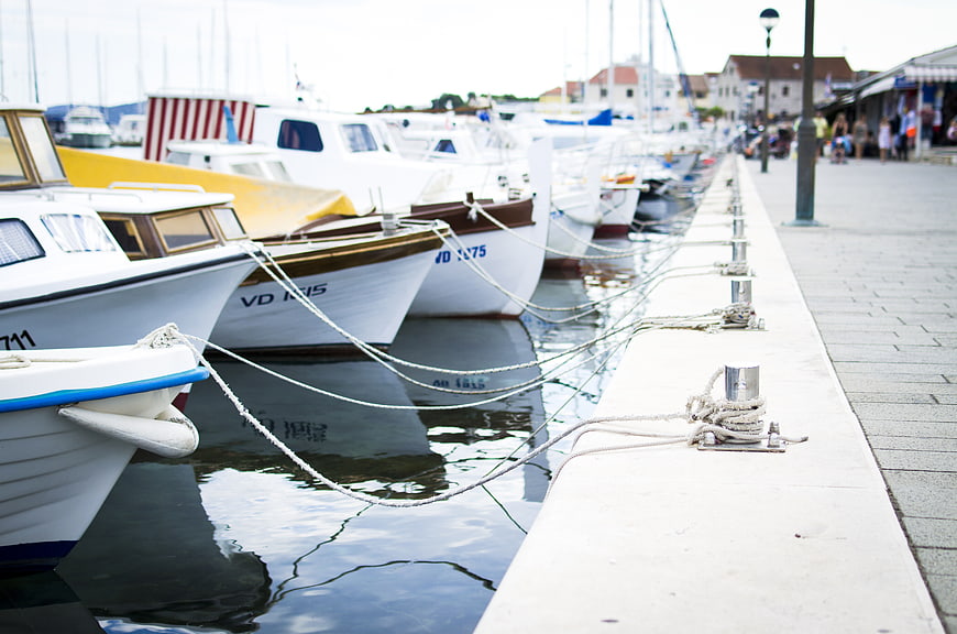 White boats docked at a harbor with ropes tied to bollards
