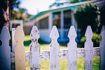 Weathered White Picket Fence With Blurred Suburban House Background