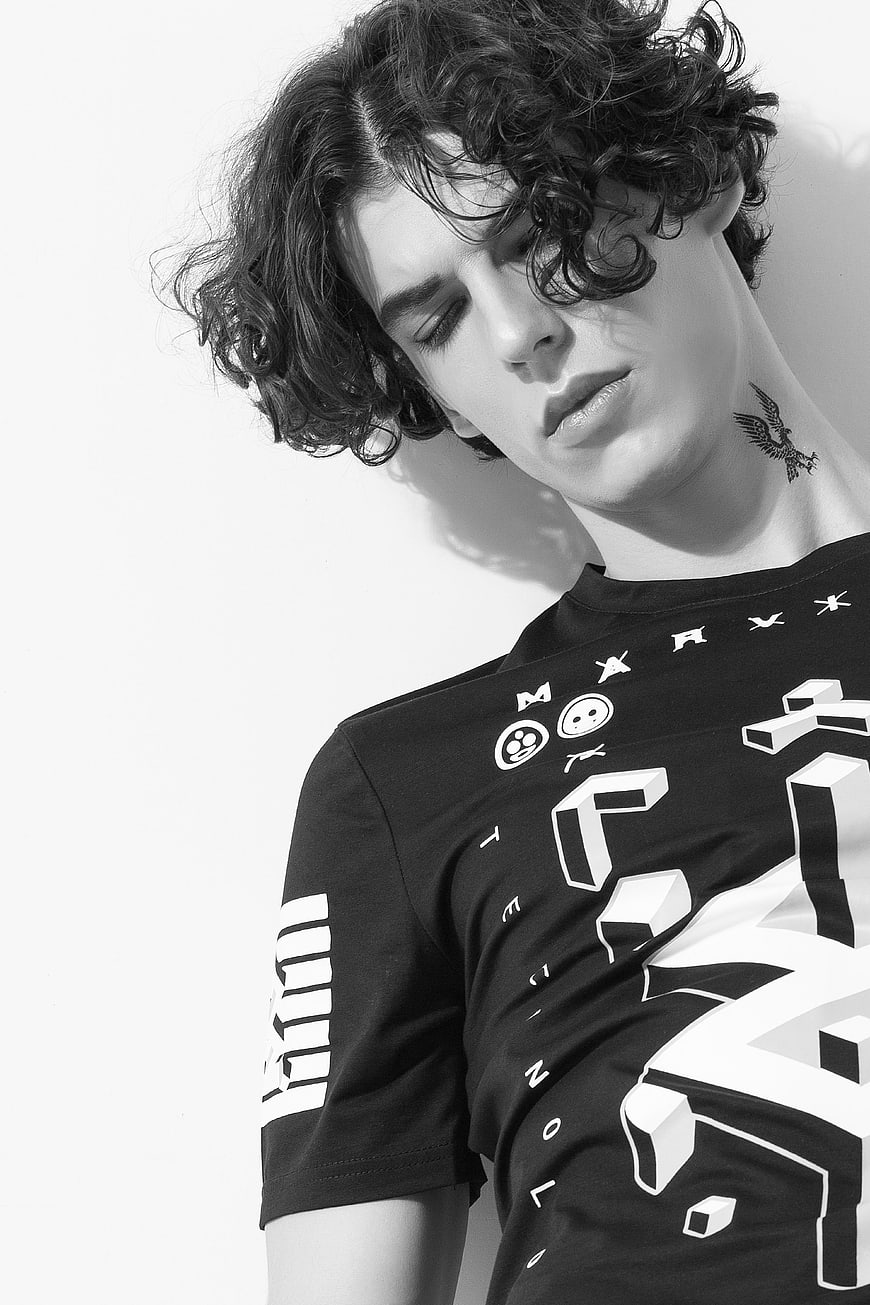 Black and white portrait of young man with curly hair and neck tattoo