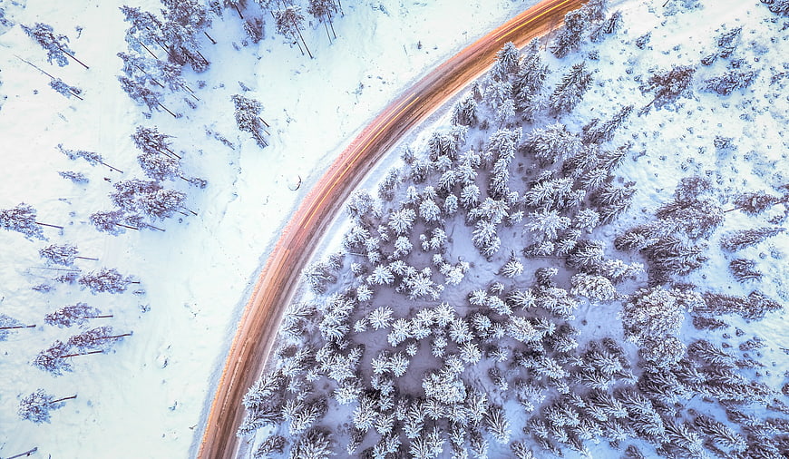 Aerial view of winding road through snowy winter forest
