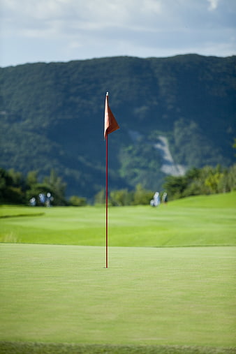 Orange golf flag on green with mountain background