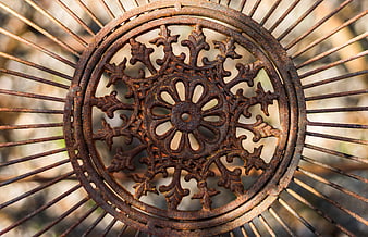 Rusty ornate iron wheel with radial spokes and floral center