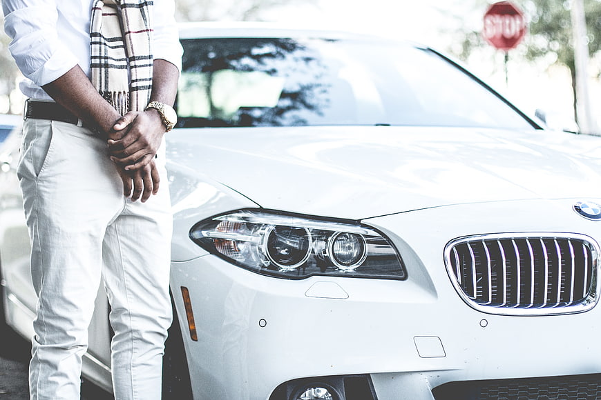 Man in Scarf Standing Next to White BMW Car