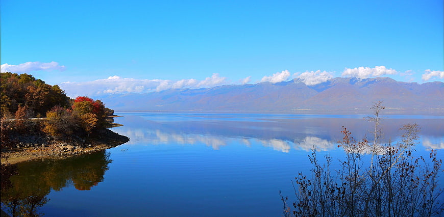 Panoramic autumn lake landscape with mountains and blue sky