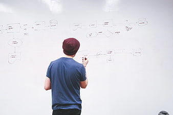 Man drawing flowchart on whiteboard in office