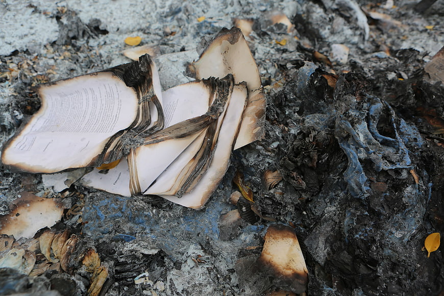 Burnt book pages in ashes and debris