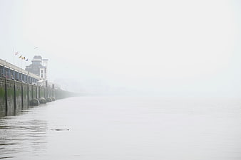 Foggy pier extending into misty calm water