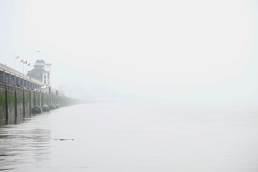 Foggy pier extending into misty calm water