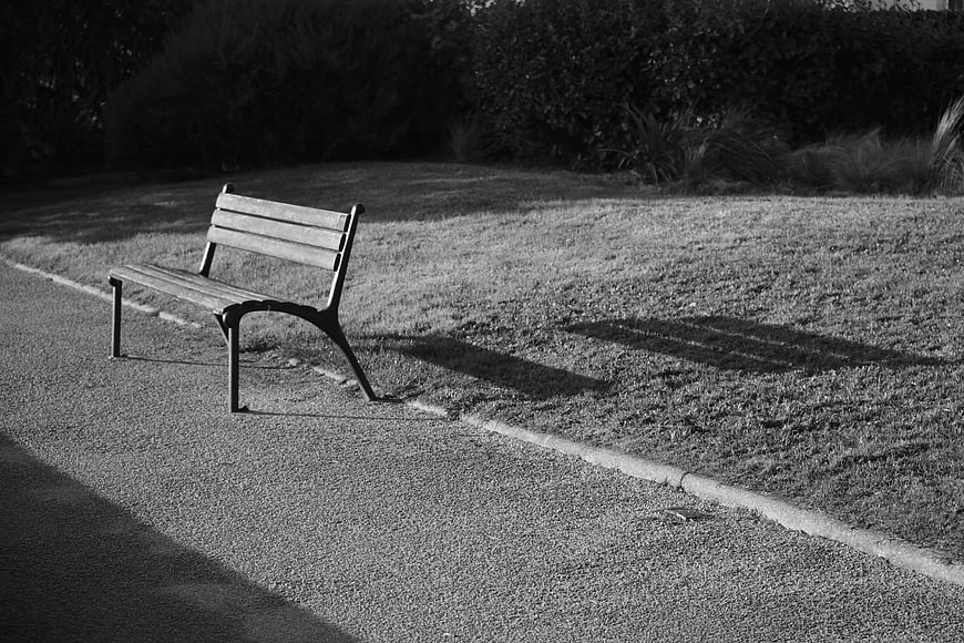 Lonely Park Bench in Black and White with Long Shadows