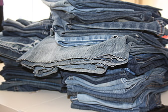 Stack of folded blue denim jeans on a white table