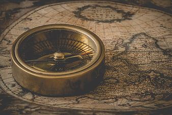 Vintage brass compass resting on an antique world map
