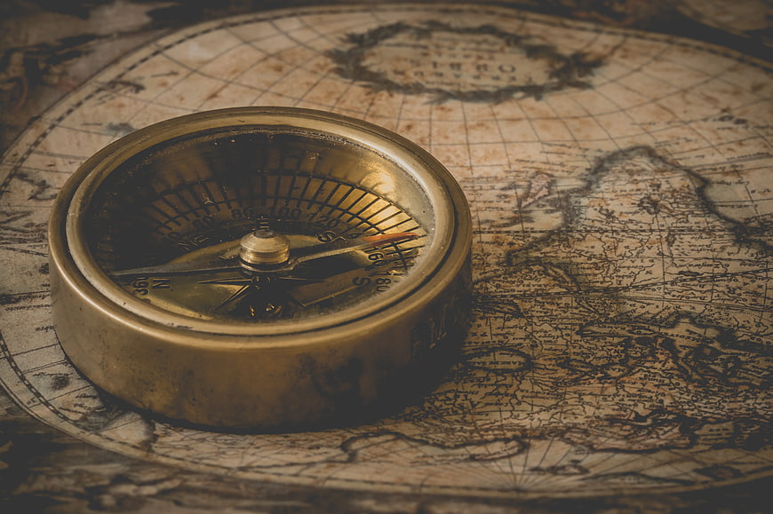 Vintage brass compass resting on an antique world map