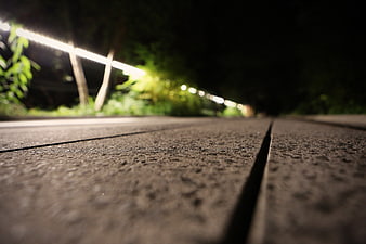Low angle night view of concrete path with blurred lights