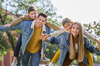 Happy family piggyback ride in park