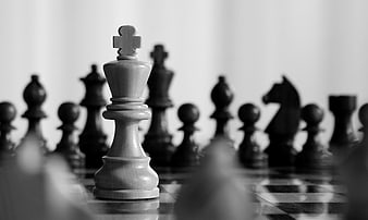 White Chess King Standing Alone Against Blurred Black Pieces