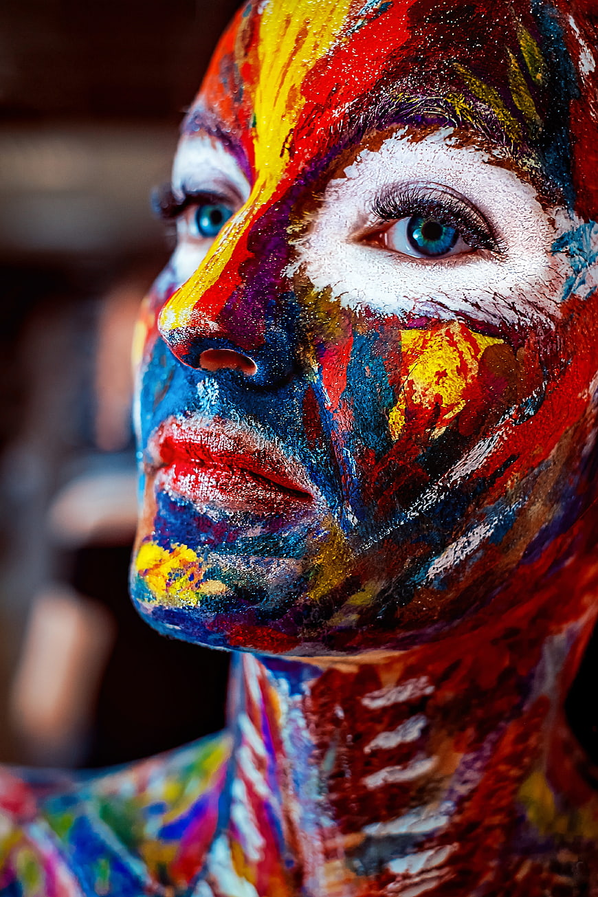 Close-up portrait of a woman with vibrant rainbow face paint