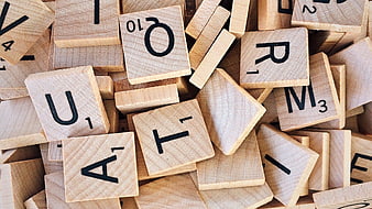 Scattered wooden Scrabble letter tiles on a pile