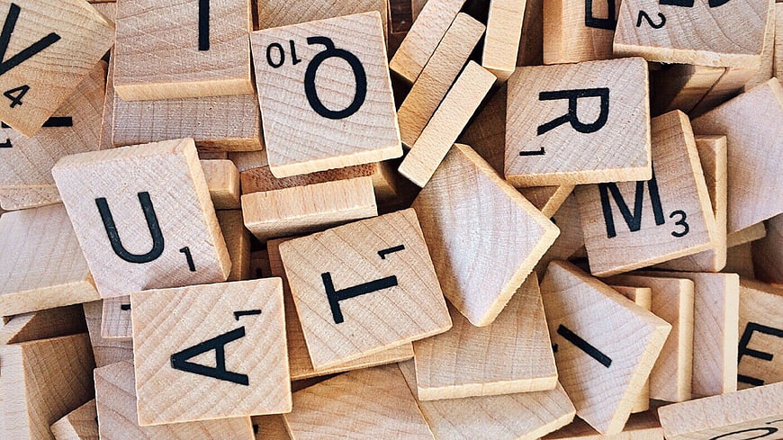 Scattered wooden Scrabble letter tiles on a pile