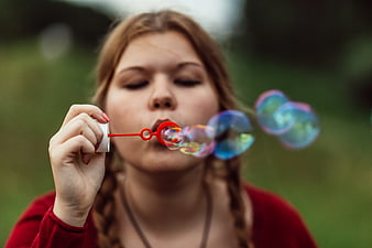 Girl Blowing Soap Bubbles with Red Wand