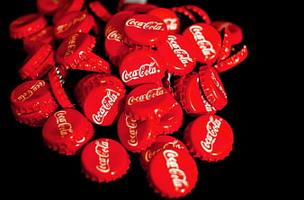 Pile of red Coca-Cola bottle caps on black background