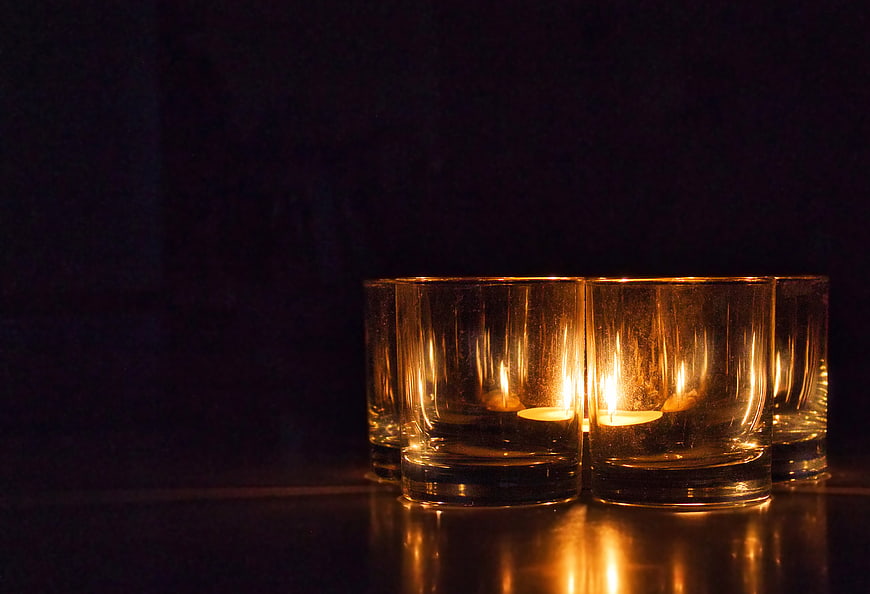 Tealight candles in textured glass holders on dark background