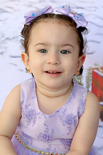 Cute toddler girl in purple dress with bows