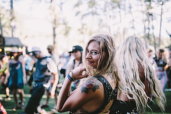 Blonde woman with tattoo smiling at outdoor music festival