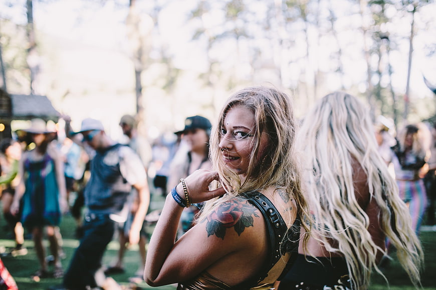 Blonde woman with tattoo smiling at outdoor music festival