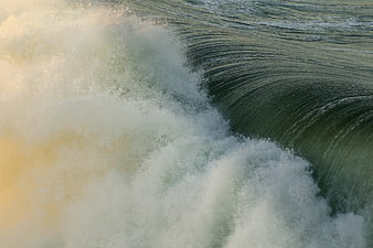 Close-up of crashing ocean wave with white foam and green water