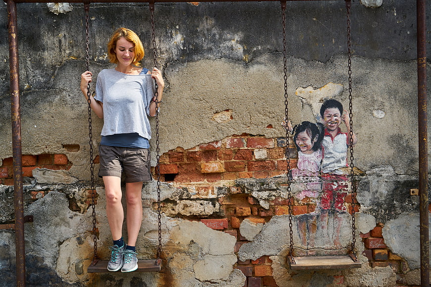 Woman on Swing Next to Street Art Mural of Children