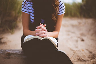 Woman Praying with Bible on Beach