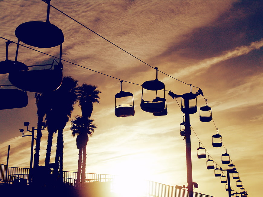 Silhouette of Chair Lifts and Palm Trees Against Golden Sunset Sky