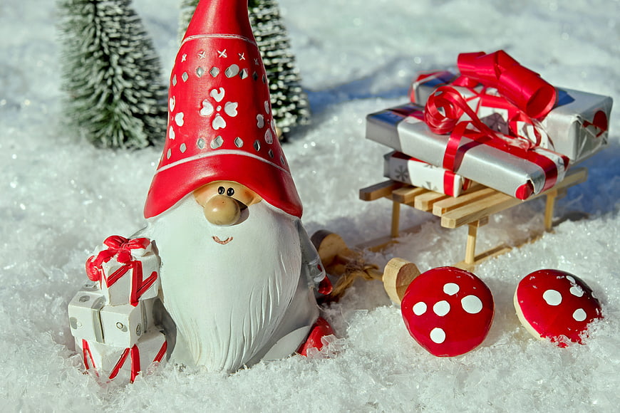 Christmas gnome with sled of gifts in snow