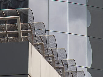 Modern metal mesh staircase railing against glass building facade