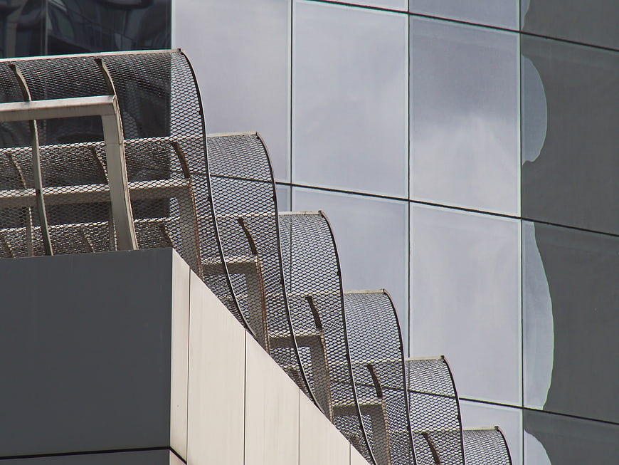 Modern metal mesh staircase railing against glass building facade