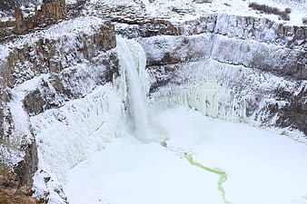 Frozen waterfall cascading into icy pool in winter landscape