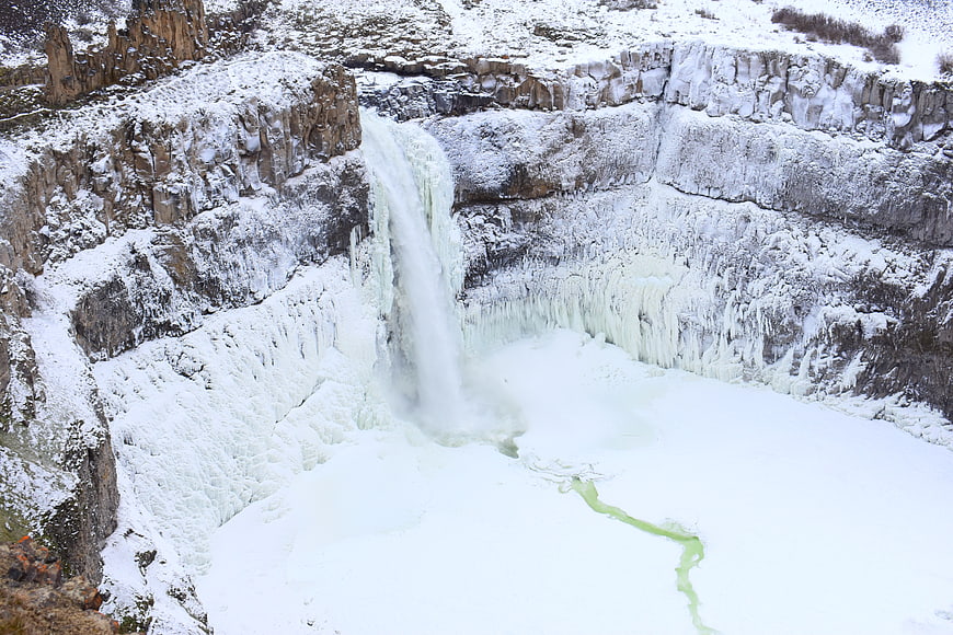 Frozen waterfall cascading into icy pool in winter landscape