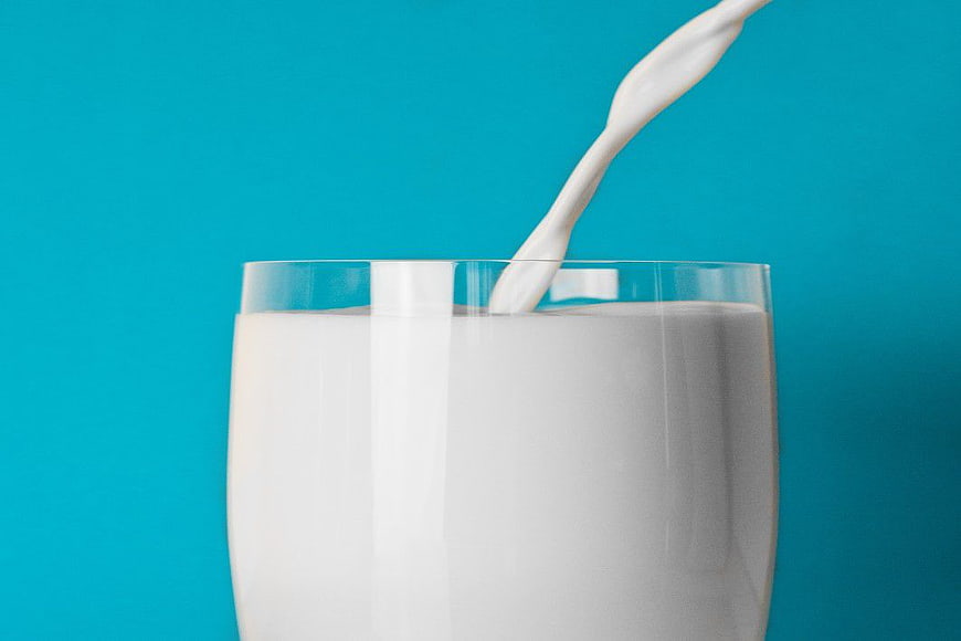 Pouring Milk into Glass on Blue Background