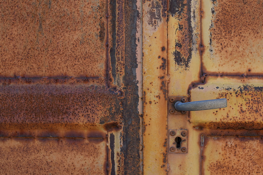 Close-up of rusty yellow metal door with handle