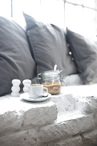 White coffee cup on rustic brick ledge with sugar jar