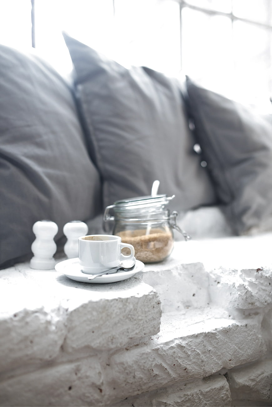 White coffee cup on rustic brick ledge with sugar jar