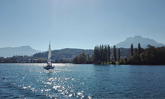Sailboat on Sparkling Lake with Mountains and Trees