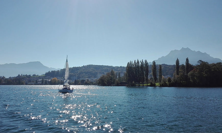 Sailboat on Sparkling Lake with Mountains and Trees